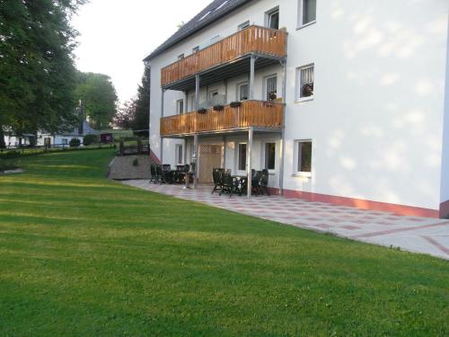 biały budynek z tarasem i trawnikiem w obiekcie Comfy Holiday Home in Burg Reuland with Sauna Terrace BBQ w mieście Burg-Reuland