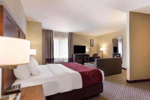 una camera d'albergo con un grande letto e una scrivania di Comfort Suites North Mobile a Saraland