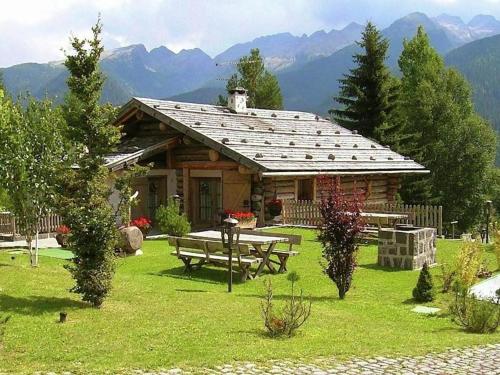a log cabin with a picnic table in the yard at Typical Cottage in Bellamonte Italy with bubble bath in Bellamonte