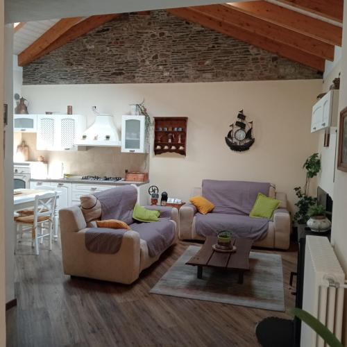 a living room with two couches and a kitchen at Casa di Dario in Pettenasco
