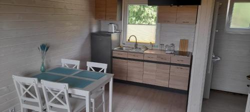 uma cozinha com uma mesa e cadeiras e um lavatório em "Morze Spokoju" domki letniskowe em Darlowko