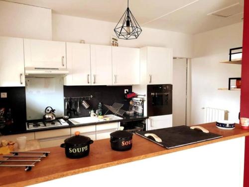 cocina con armarios blancos y encimera de madera en Maison familiale - ménage, serviettes, draps inclus, en Gaillac