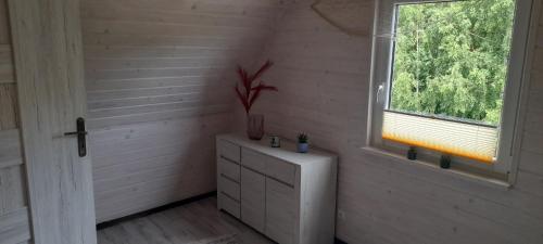 a white room with a window and a white dresser at "Morze Spokoju" domki letniskowe in Darłówko