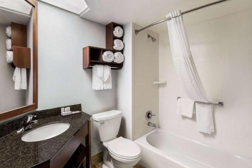 a bathroom with a toilet and a sink and a tub at AmericInn by Wyndham Madison West in Madison