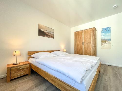 een slaapkamer met een groot bed en een houten kast bij Weiße Villen Wohnung 20 in Boltenhagen