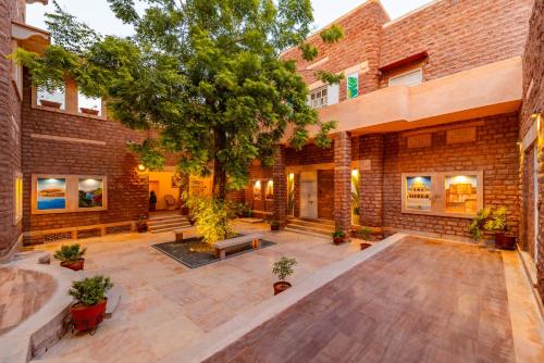 einen leeren Innenhof mit einem Baum und einem Backsteingebäude in der Unterkunft Tree Of Life Bhadrajun House, Jodhpur in Jodhpur