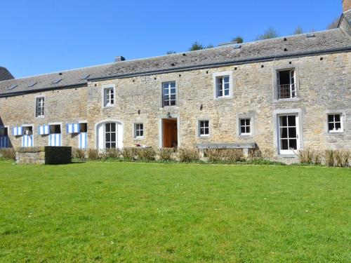 un antiguo edificio de piedra con un campo de césped delante de él en Cosy Cottage in Barvaux Condroz with Garden, en Barvaux-Condroz