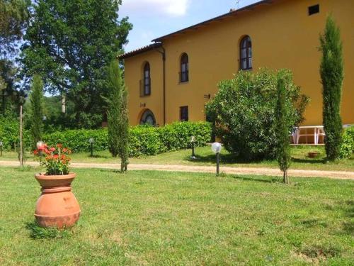 a flower pot in the grass in front of a building at Restful Farmhouse near Forest in Vinci with Pool in Vinci