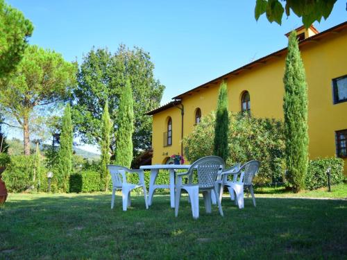 a table and chairs in the grass in front of a building at Restful Farmhouse near Forest in Vinci with Pool in Vinci