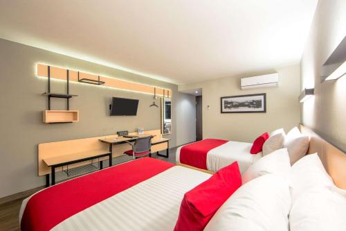 a hotel room with two beds and a desk at Comfort Inn Delicias in Delicias