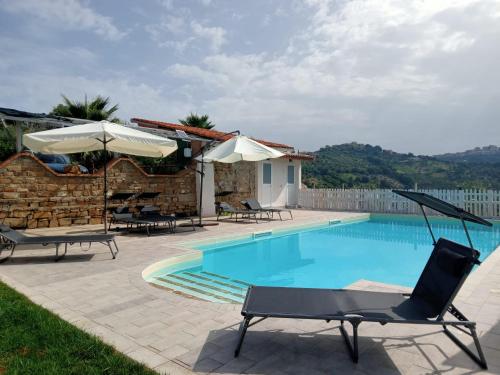 a swimming pool with chairs and umbrellas next to a house at Casale 920 in Agropoli