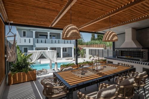 un patio con tavolo, sedie e piscina di Fratelli Villa, with Heated Pool & Jacuzzi, By ThinkVilla ad Áyios Kírikos