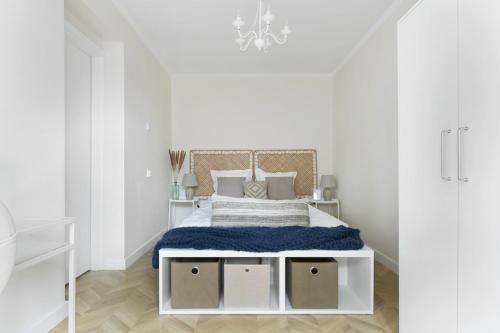 a white bedroom with a bed with a blue blanket at Elite Apartments Center Superior in Gdańsk