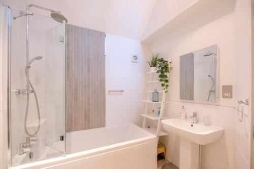 a white bathroom with a shower and a sink at Kipper Cottage in Southwold