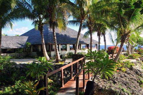 a wooden path leading to a resort with palm trees at White Grass Ocean Resort & Spa in Tanna Island
