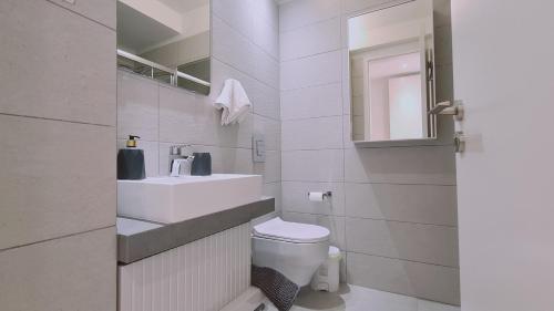 a bathroom with a sink and a toilet and a mirror at STAY Mediterranean Waves Apartment in Paralimni