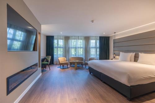 デン・ハーグにあるブティックホテル コロナのベッド、テーブル、椅子が備わるホテルルームです。