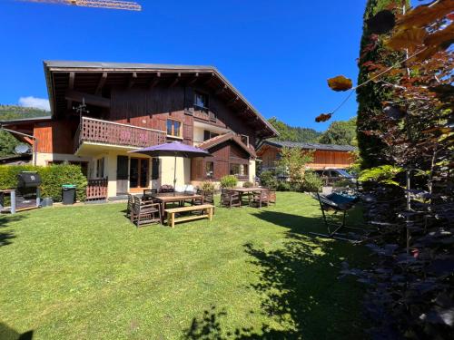 a house with a yard with chairs and an umbrella at Chalet Aventure B&B Les Gets in Les Gets
