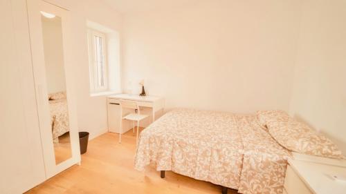 a white bedroom with a bed and a desk at Alojamiento Nevada in La Zubia