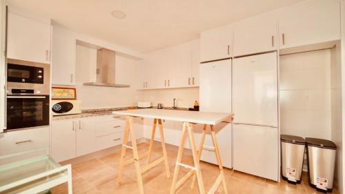 a kitchen with white cabinets and a white table at Alojamiento Nevada in La Zubia