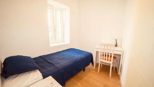 a bedroom with a bed and a chair and a window at Alojamiento Nevada in La Zubia
