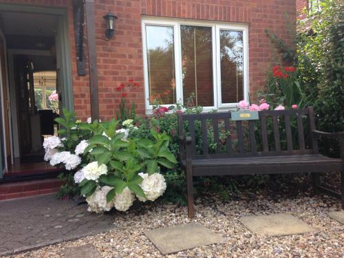 a bench in front of a house with flowers at Bindons in Taunton