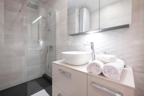 La salle de bains est pourvue d'un lavabo blanc et d'une douche. dans l'établissement Sommeiller à 2 min du Lac, à Annecy