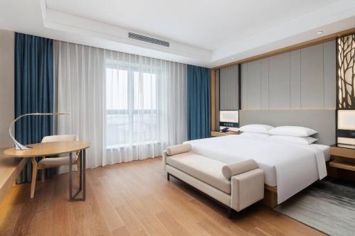 杭州市にあるCourtyard by Marriott Hangzhou Westのベッドルーム(白いベッド1台、テーブル、椅子付)