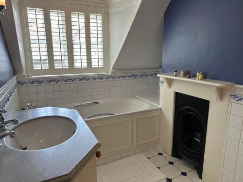 baño con bañera, lavamanos y chimenea en The Old Butchers in Hambleden en Henley on Thames