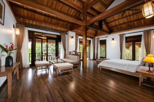 a bedroom with a bed and a living room at Mai Chau Hideaway Lake Resort in Mai Chau