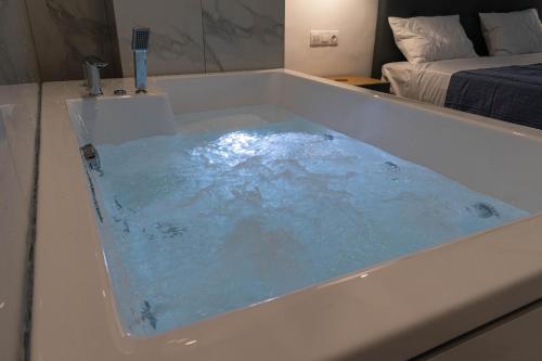 eine Badewanne mit blauem Wasser in einem Schlafzimmer in der Unterkunft Athens Jacuzzi apartment in Athen