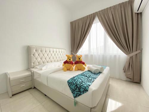 two stuffed animals sitting on a bed in a bedroom at Langkawi Simfoni Beliza Apartment with Sky Pool by Zervin in Kuah