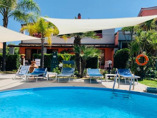 una piscina con sillas azules y una sombrilla blanca en Hotel Elba en Marina di Campo