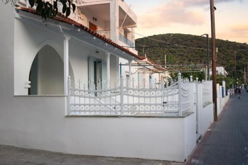 a white building with a white fence on a street at Nonta's Luxury Home in Megalochori