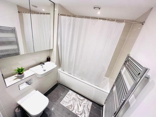 een badkamer met een toilet, een wastafel en een spiegel bij London 2 Beds Flat Next to the City in Londen