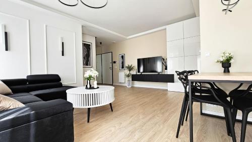 a living room with a black couch and a table at Apartament Wietrznia z tarasem, ogródkiem, parkingiem, na prestiżowym osiedlu obok rezerwatu przyrody NEW!!! in Kielce