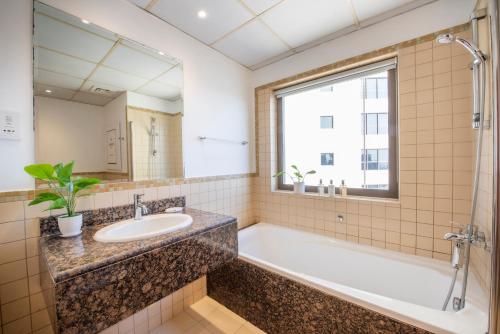 een badkamer met een bad, een wastafel en een spiegel bij Nasma Luxury Stays- Incredibly Spacious Apt Overlooking The Marina in Dubai