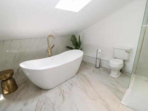 a white bathroom with a tub and a toilet at The Old House in Northallerton