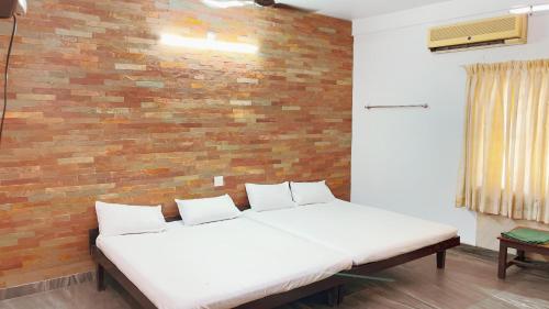 a white bed in a room with a brick wall at PPG HOMES in Ernakulam
