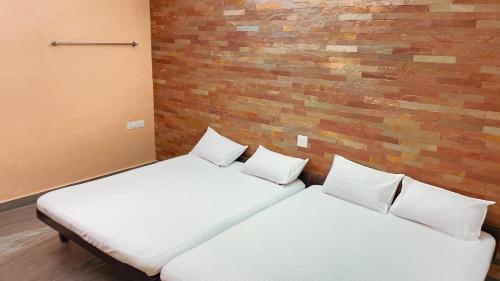 two beds in a room with a brick wall at PPG HOMES in Ernakulam