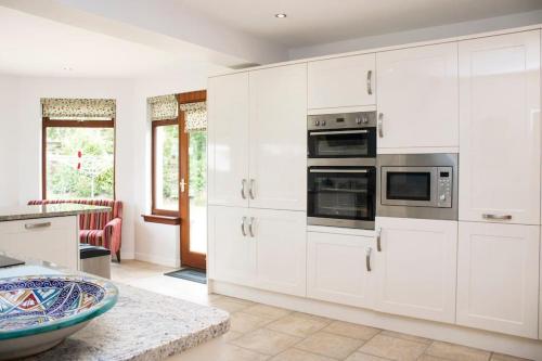 a kitchen with white cabinets and a counter top at Pear Tree Cottage in Limekilns