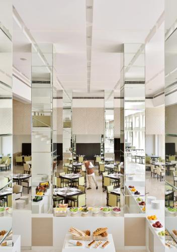 Ein Esszimmer mit Tischen und eine im Hintergrund vorbeigehende Person in der Unterkunft Jaisalmer Marriott Resort & Spa in Jaisalmer