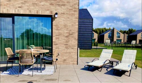 a patio with a table and chairs next to a brick building at Makin' Memories - Apartamentai Monciškėse in Palanga