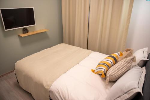 a bedroom with a white bed with a tv on the wall at Cross Caraiman View 1 in Buşteni