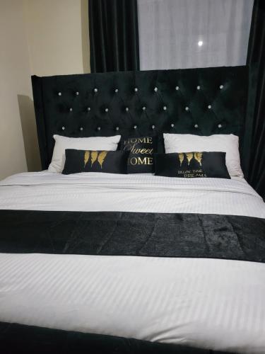 ein Bett mit einem schwarzen Kopfteil und Kissen darauf in der Unterkunft G&G Executive Homes NAKURU in Nakuru