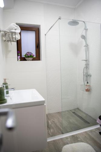 a white bathroom with a shower and a sink at Cross Caraiman View 1 in Buşteni