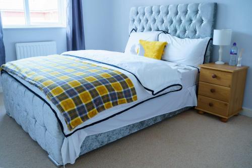 a blue bedroom with a bed and a night stand at Millward Homes in Bletchley