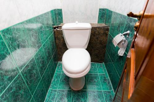 a bathroom with a white toilet in a green tiled room at USSR Hostel in Bishkek