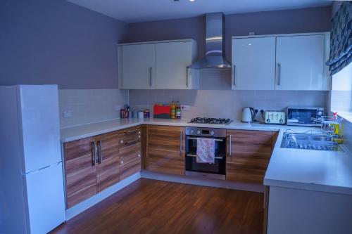 a kitchen with white appliances and wooden cabinets at Millward Homes in Bletchley