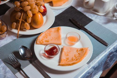 a table with two plates of food with bread and fruit at Reikartz Kokand in Kokand